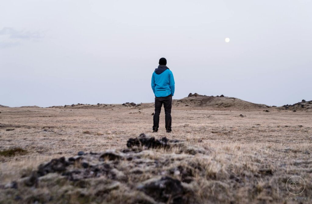 Man in Blue Hoodie Standing on Brown Grass