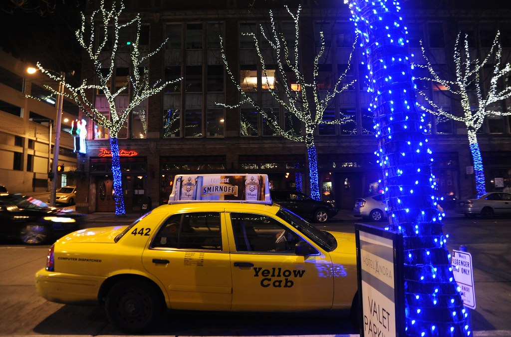 Yellow cab 442 with ad, Holiday Lights glowing on trees in blue and white, vehicles, Valet Parking, downtown, Seattle, Washington, USA